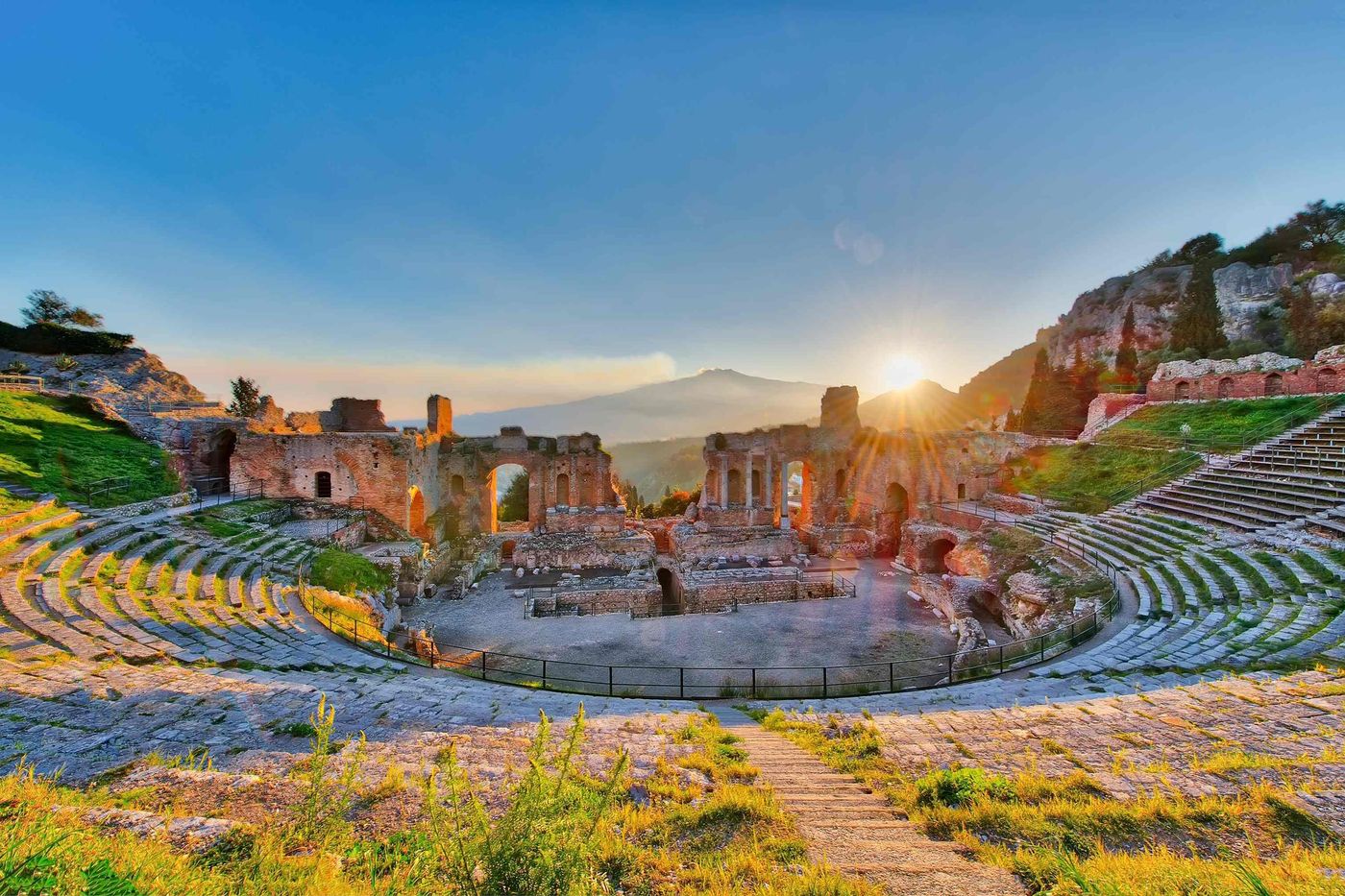 Ancient theatre of Taormina Siciliy Italy with Etna erupting volcano at sunset sm