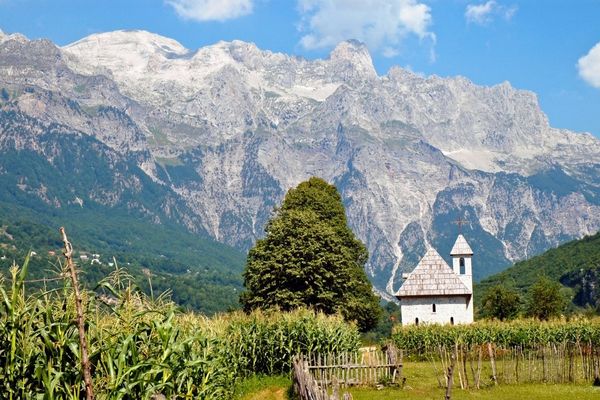Small white stone chapel set against the dramatic peaks of the Albanian Alps, Balkans walking holiday route