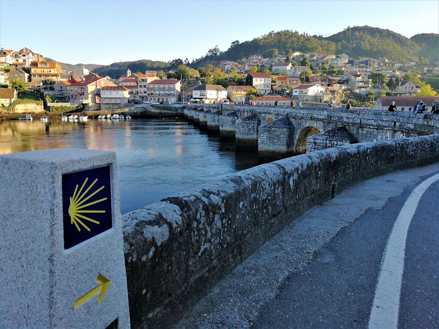 Camino-de-Santiago-Marker-by-Medieval-Bridge-and-Coastal-Town