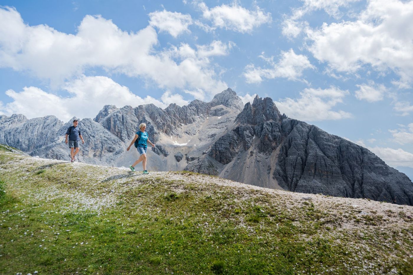 Couple hiking on a framed by the massive and jagged limestone face of the Cristallo massif- supplied by funactive