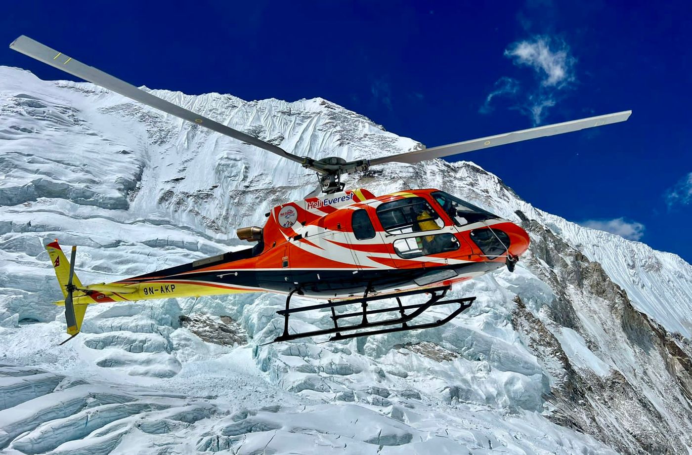 Helicopter in the air next to mountain