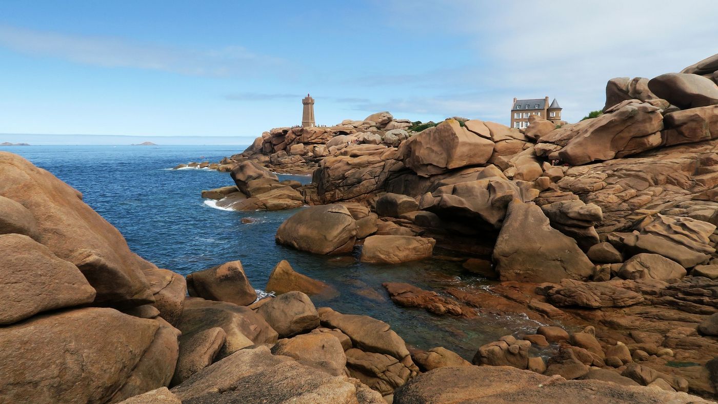 Pink granite boulders with a view of the Mean Ruz lighthouse Ploumanac'h. Brittany France