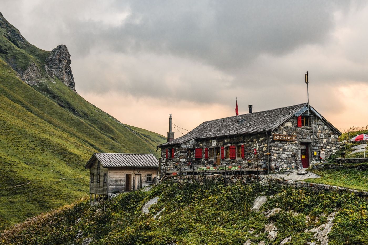 The rustic stone Rotstockhütte mountain cabin sits near Mürren under an overcast sky in the Swiss Alps